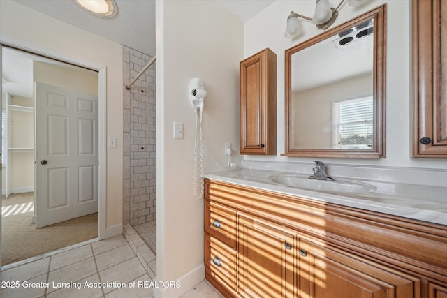 bathroom with tiled shower, tile patterned floors, and vanity