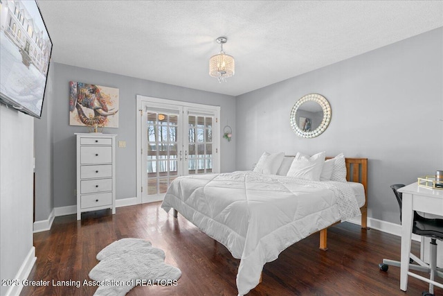 bedroom with an inviting chandelier, dark hardwood / wood-style floors, a textured ceiling, access to outside, and french doors