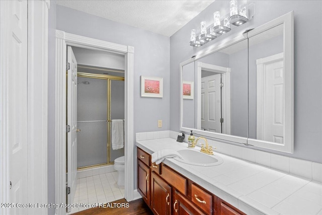 bathroom with vanity, an enclosed shower, a textured ceiling, and toilet