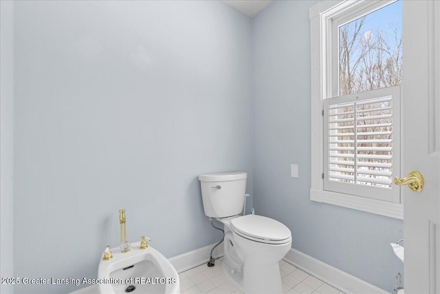 bathroom featuring a bidet, tile patterned floors, toilet, and a wealth of natural light