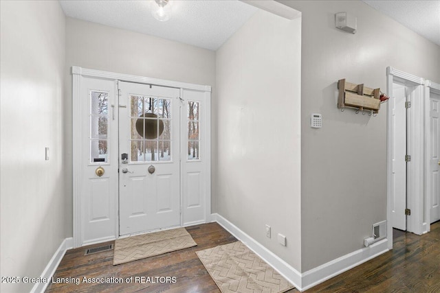 entryway with dark wood-type flooring and a textured ceiling