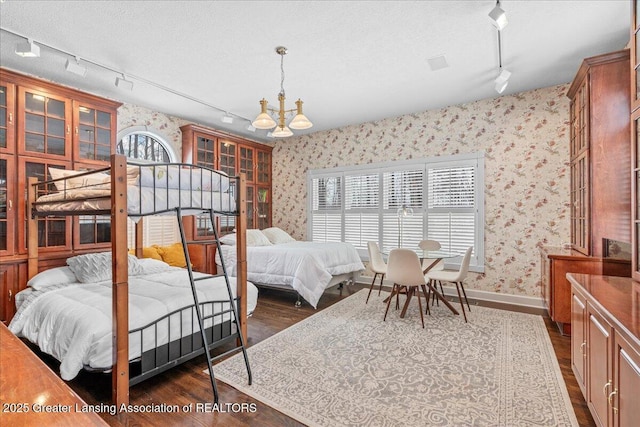 bedroom featuring a chandelier, dark hardwood / wood-style floors, track lighting, and a textured ceiling