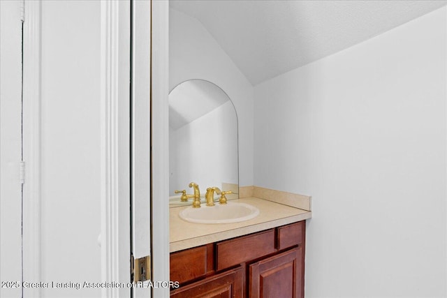 bathroom featuring lofted ceiling, vanity, and a textured ceiling