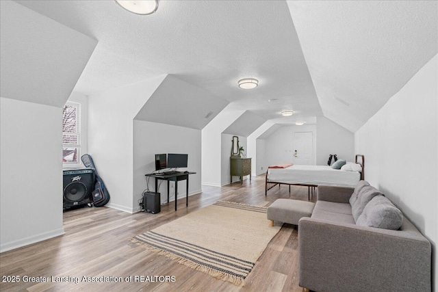 bedroom featuring vaulted ceiling, a textured ceiling, and light wood-type flooring