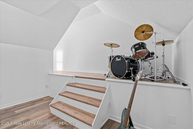 stairway with wood-type flooring, lofted ceiling, and a textured ceiling