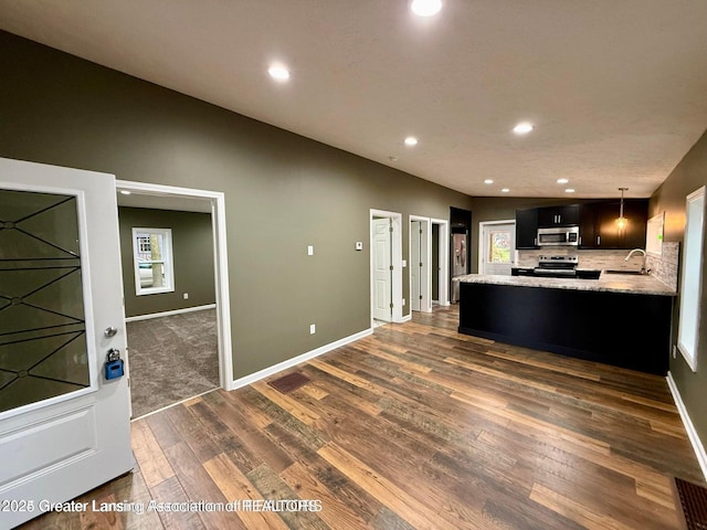 kitchen featuring appliances with stainless steel finishes, sink, dark hardwood / wood-style flooring, hanging light fixtures, and kitchen peninsula