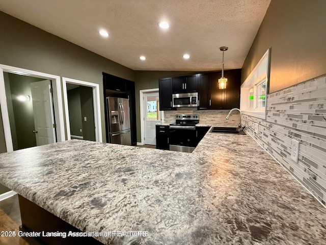 kitchen featuring decorative light fixtures, sink, kitchen peninsula, stainless steel appliances, and a textured ceiling