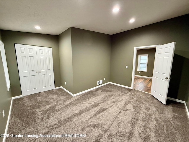 unfurnished bedroom featuring dark carpet and a closet