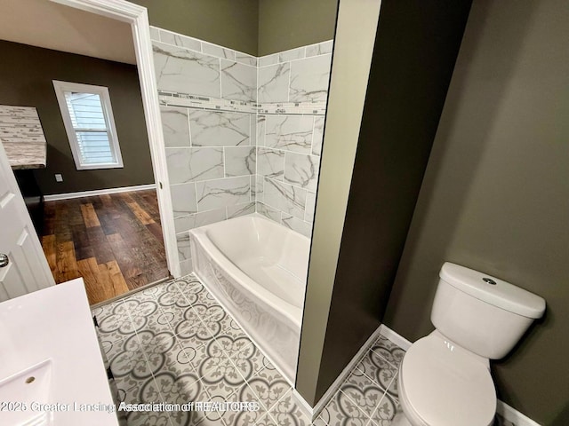 bathroom with hardwood / wood-style flooring, tiled shower / bath, and toilet