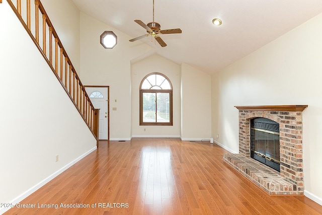 unfurnished living room with ceiling fan, a fireplace, high vaulted ceiling, and light hardwood / wood-style flooring