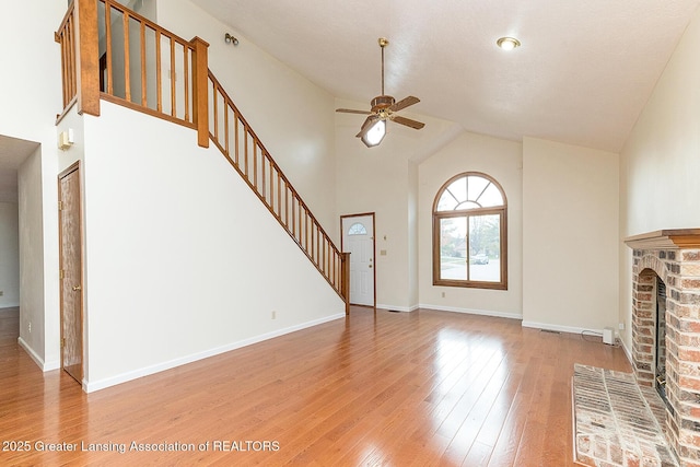 unfurnished living room with a brick fireplace, wood-type flooring, ceiling fan, and vaulted ceiling