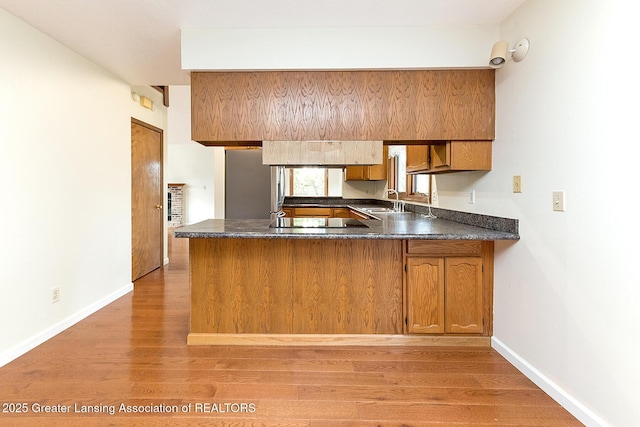 kitchen featuring sink, black electric stovetop, light wood-type flooring, and kitchen peninsula