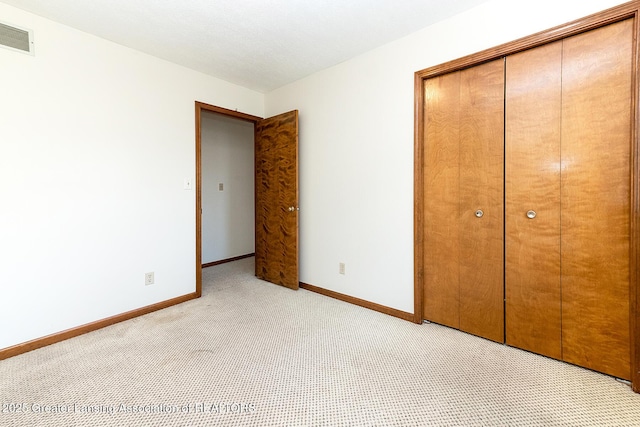 unfurnished bedroom with light colored carpet and a closet