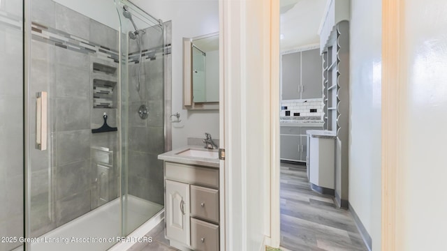 bathroom with vanity, decorative backsplash, a shower with door, and hardwood / wood-style flooring