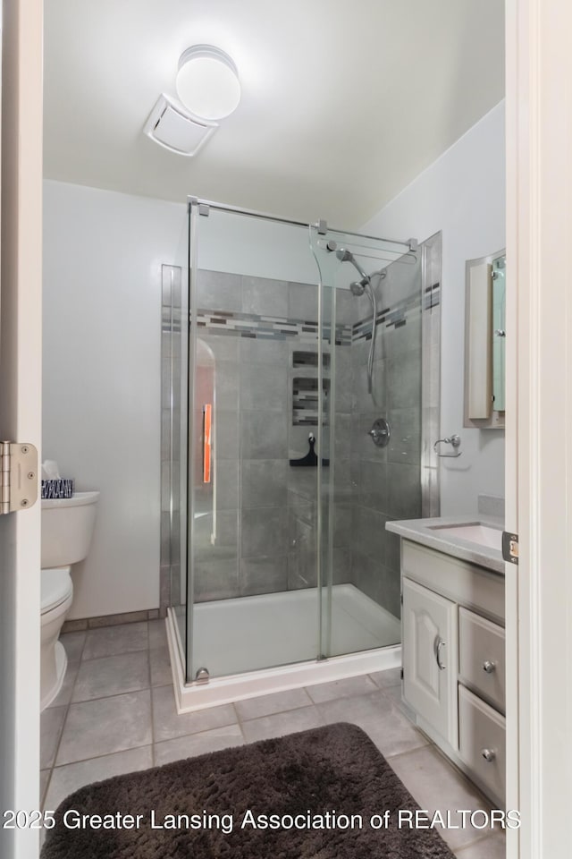 bathroom featuring tile patterned flooring, vanity, a shower with shower door, and toilet