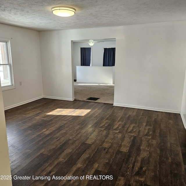 empty room featuring dark wood-type flooring, ceiling fan, and a textured ceiling