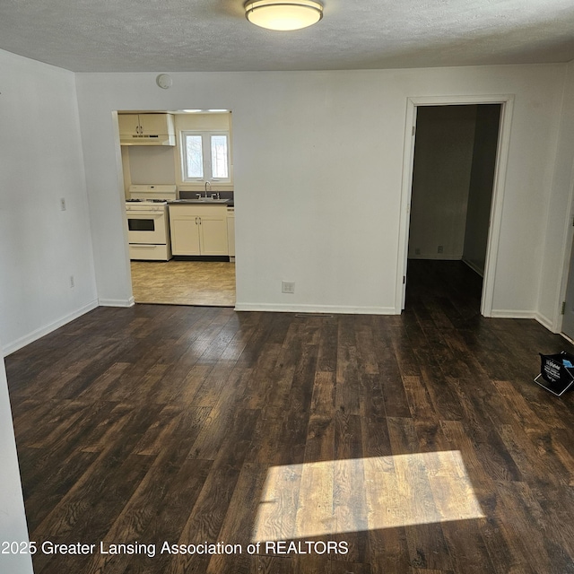 empty room with sink, a textured ceiling, and dark hardwood / wood-style flooring