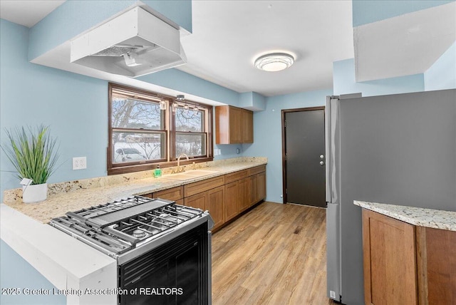 kitchen featuring light stone counters, sink, light hardwood / wood-style flooring, and stainless steel appliances