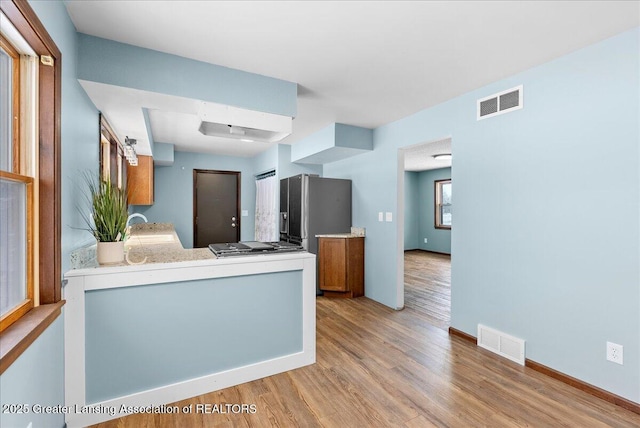 kitchen with stainless steel appliances, sink, kitchen peninsula, and light hardwood / wood-style floors