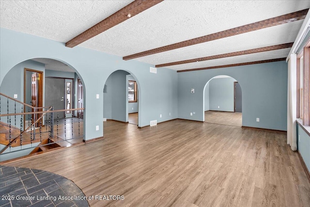 living room with hardwood / wood-style flooring, a textured ceiling, and beamed ceiling