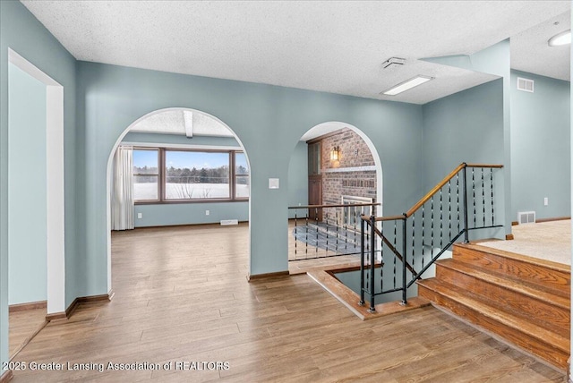 interior space with hardwood / wood-style flooring, a baseboard radiator, and a textured ceiling