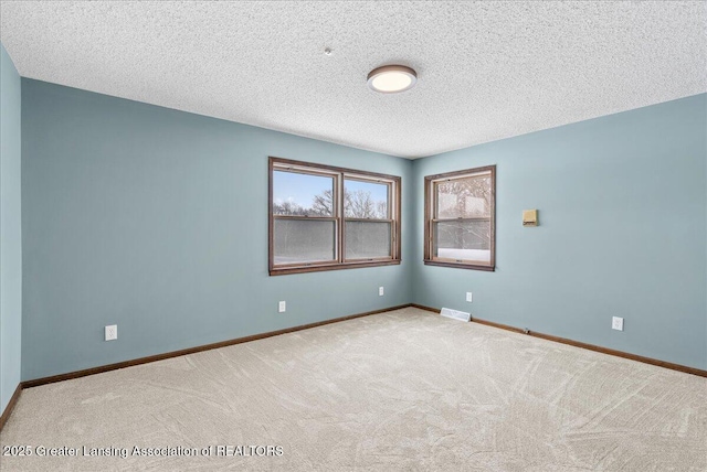 carpeted empty room featuring a textured ceiling