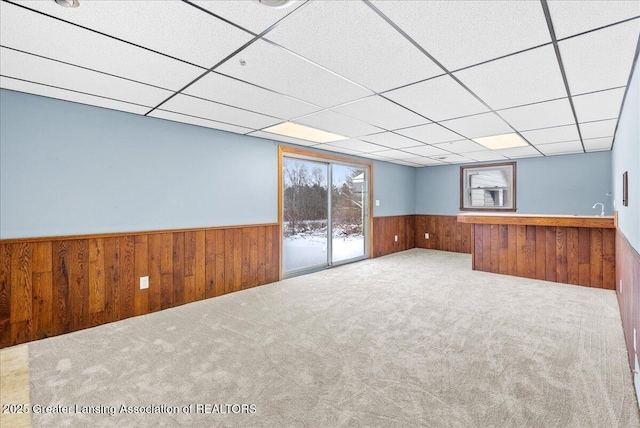 interior space with a paneled ceiling and wood walls