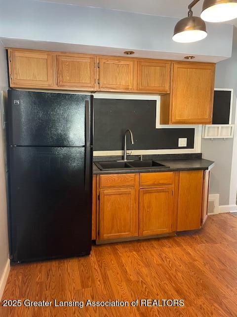 kitchen with black fridge, sink, and light hardwood / wood-style floors