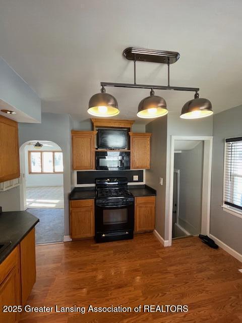 kitchen featuring hanging light fixtures, dark wood-type flooring, and black appliances