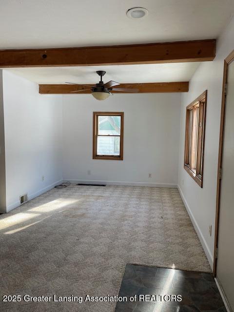 empty room with ceiling fan, carpet floors, and beamed ceiling