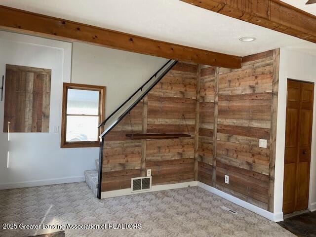 bonus room with carpet flooring, beam ceiling, and wood walls