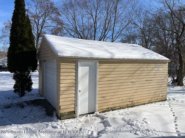 snow covered structure featuring a garage