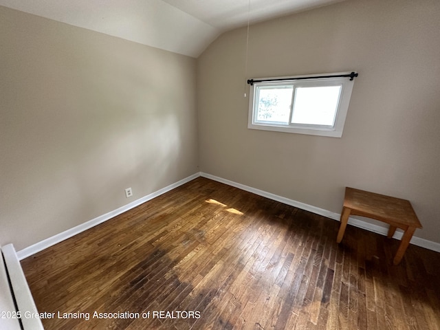 unfurnished room with dark wood-type flooring and lofted ceiling