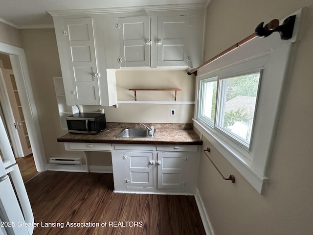 kitchen featuring dark hardwood / wood-style floors, built in desk, sink, white cabinets, and ornamental molding