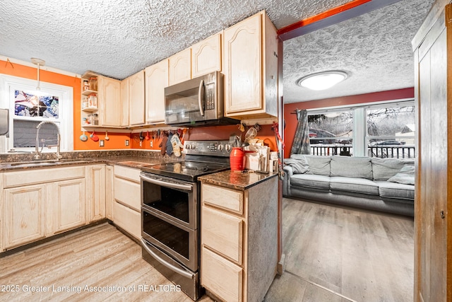 kitchen with sink, appliances with stainless steel finishes, light brown cabinets, decorative light fixtures, and light wood-type flooring