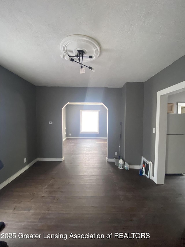 unfurnished living room featuring a textured ceiling and dark hardwood / wood-style flooring