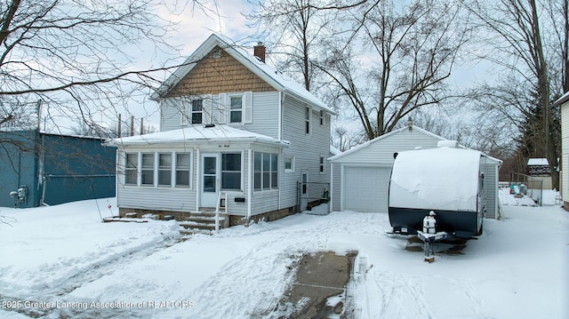 snow covered house with a garage, a sunroom, and an outbuilding