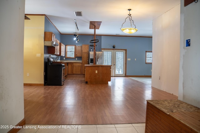 kitchen with appliances with stainless steel finishes, pendant lighting, ornamental molding, a center island, and light hardwood / wood-style floors