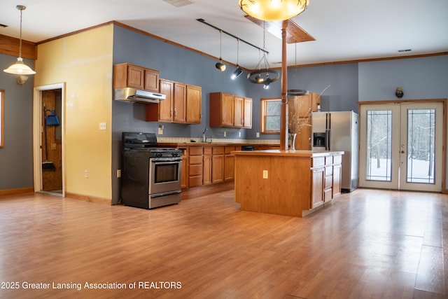 kitchen featuring sink, light hardwood / wood-style flooring, hanging light fixtures, stainless steel appliances, and a kitchen island