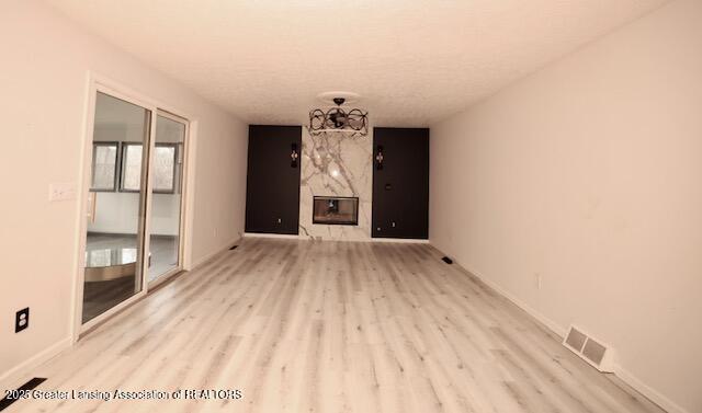 unfurnished living room featuring a premium fireplace and light hardwood / wood-style floors