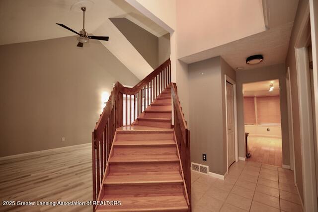 staircase with tile patterned flooring, a towering ceiling, and ceiling fan