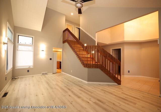 unfurnished living room featuring ceiling fan, light wood-type flooring, and high vaulted ceiling