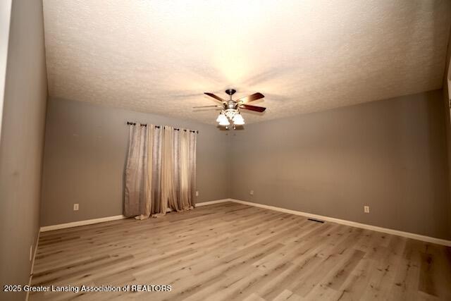 spare room featuring ceiling fan, light hardwood / wood-style flooring, and a textured ceiling