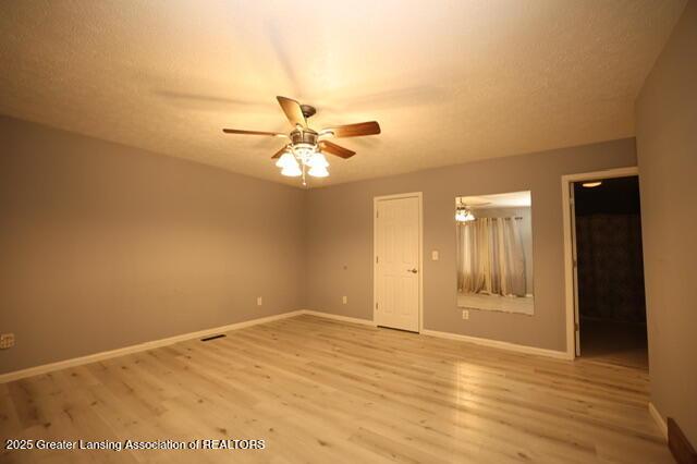 empty room with ceiling fan, a textured ceiling, and light hardwood / wood-style floors