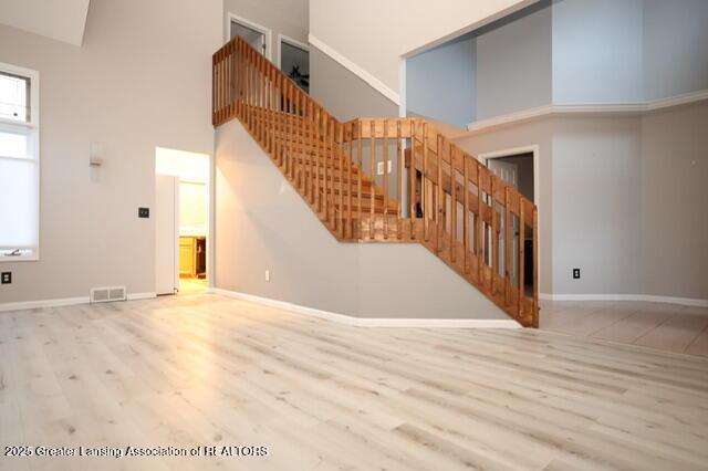 unfurnished living room featuring a towering ceiling and light hardwood / wood-style floors