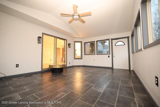 unfurnished living room with ceiling fan and vaulted ceiling