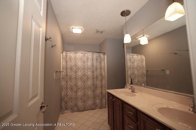 bathroom featuring vanity, tile patterned flooring, and a textured ceiling