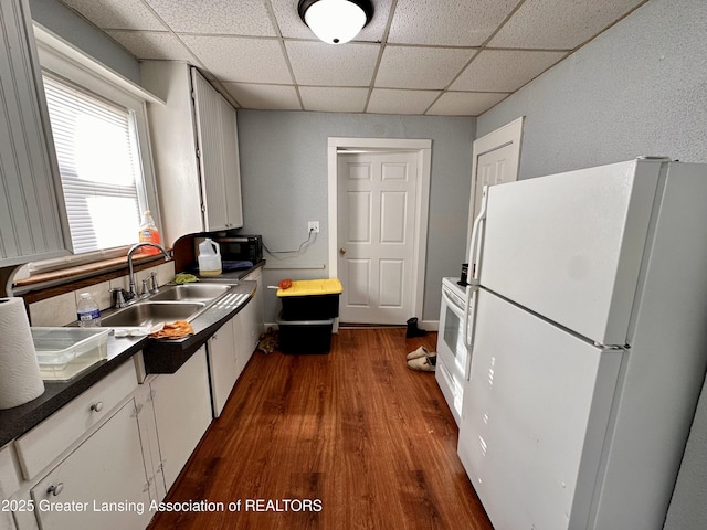 kitchen with sink, a paneled ceiling, dark hardwood / wood-style flooring, white appliances, and white cabinets