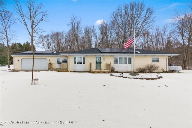 snow covered property featuring a garage and solar panels