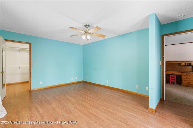 unfurnished bedroom featuring ceiling fan, a spacious closet, light hardwood / wood-style floors, and a closet